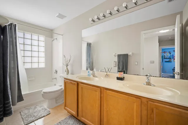 a bathroom with a double vanity sink toilet mirror and bathtub
