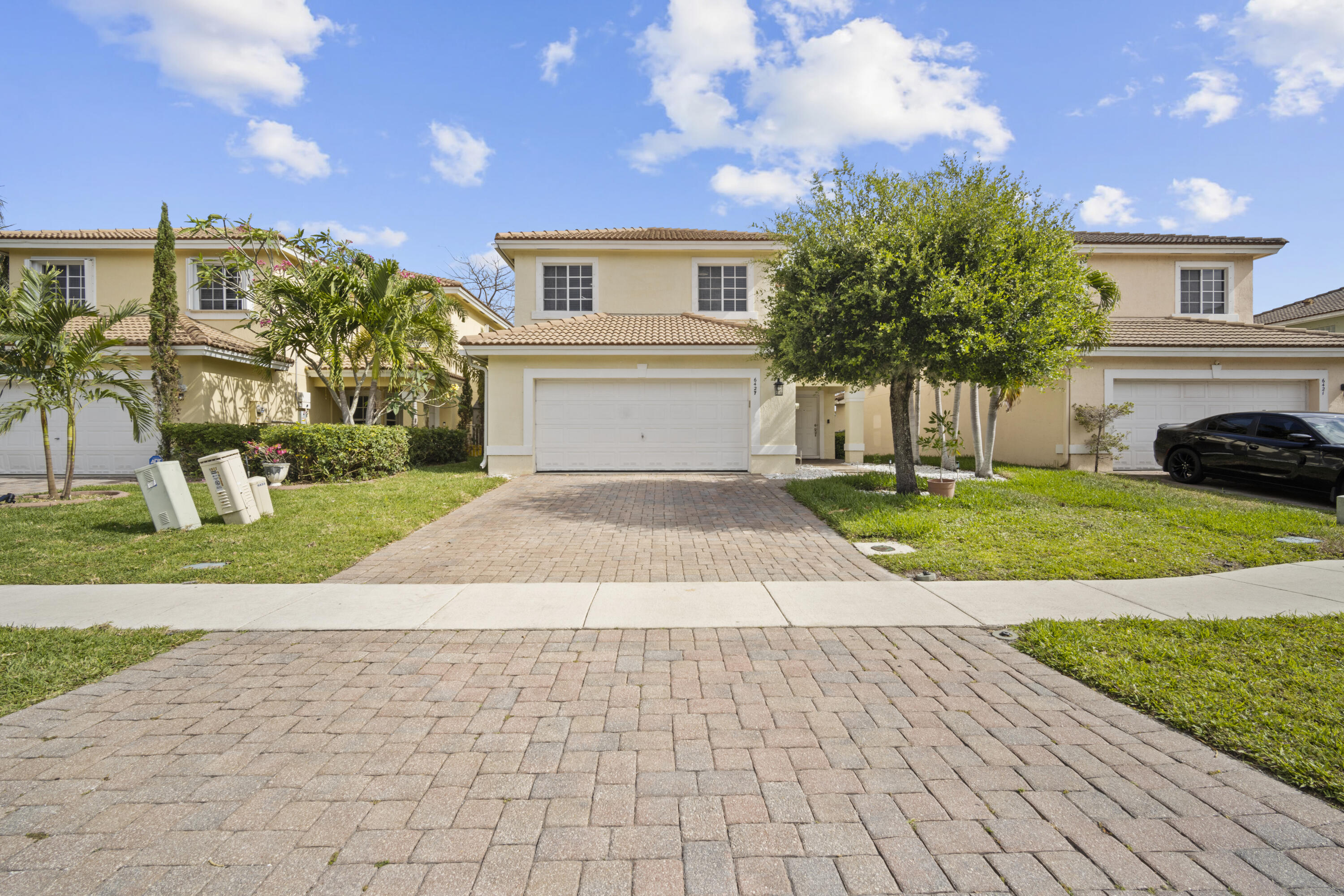 6427 Adriatic Way Greenacres, FL 33413 - Photo 2 of 33 a front view of a house with a yard and potted plants