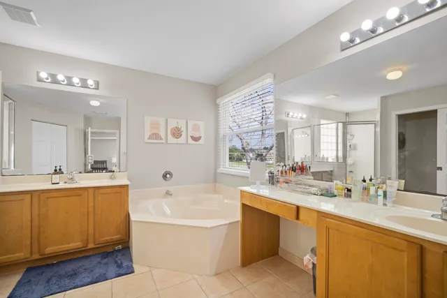 a bathroom with a tub a double vanity sink and mirror
