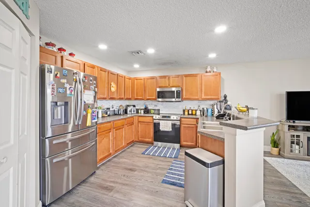 a kitchen with stainless steel appliances granite countertop a refrigerator and a stove top oven