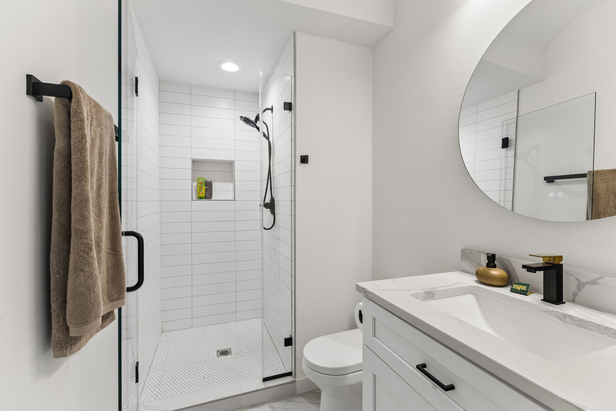 5305 Ledesma Road, Unit 1 Austin, TX 78721 - Photo 11 of 26 Modern bathroom featuring a glass-enclosed shower with white subway tile, a built-in shower niche, and a contrasting black showerhead