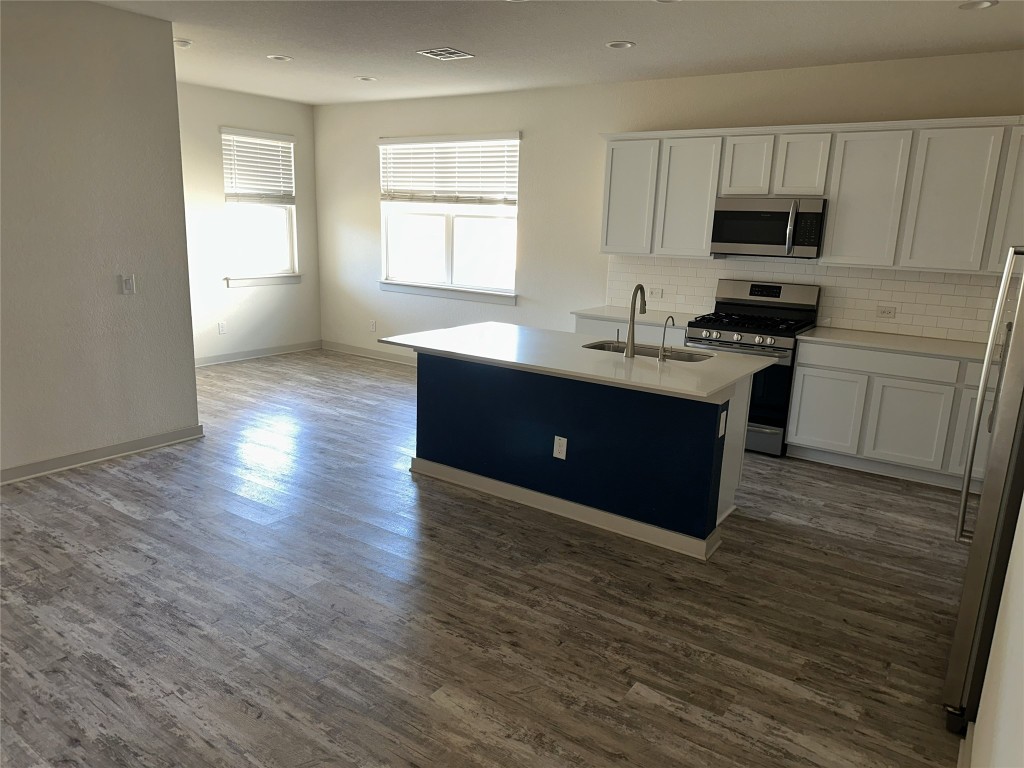 241 Deserti Road Leander, TX 78641 - Photo 5 of 24 a kitchen with granite countertop a stove and a wooden floor
