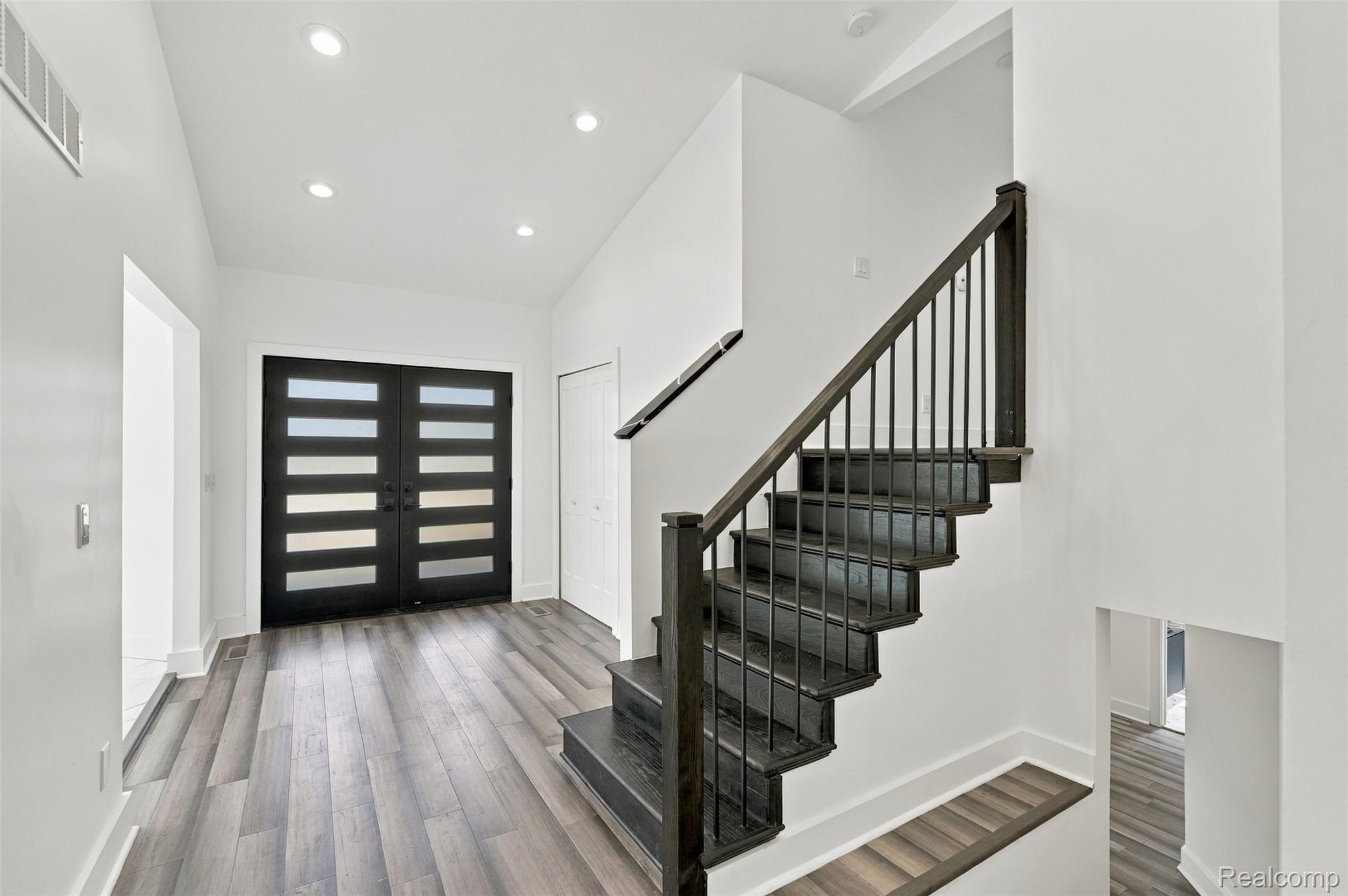 27507 Bell Road Southfield, MI 48034 - Photo 9 of 81 Modern double entry doors with frosted glass panels, wood-finish flooring, recessed ceiling lighting, and a contemporary dark wood staircase with metal balusters