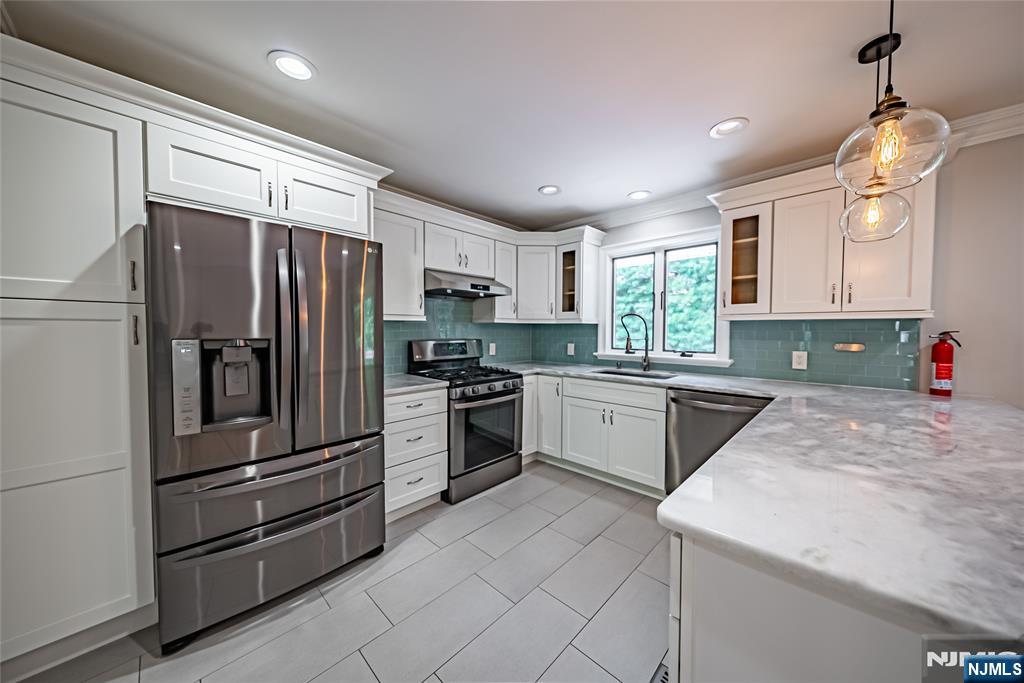 71 Columbus Road Demarest, NJ 07627 - Photo 9 of 50 a kitchen with granite countertop a refrigerator oven a sink dishwasher and white cabinets with wooden floor