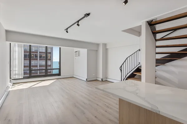 a view of an empty room with stairs and a window