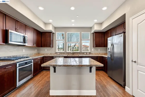 a kitchen with stainless steel appliances granite countertop a sink a stove a refrigerator and a microwave