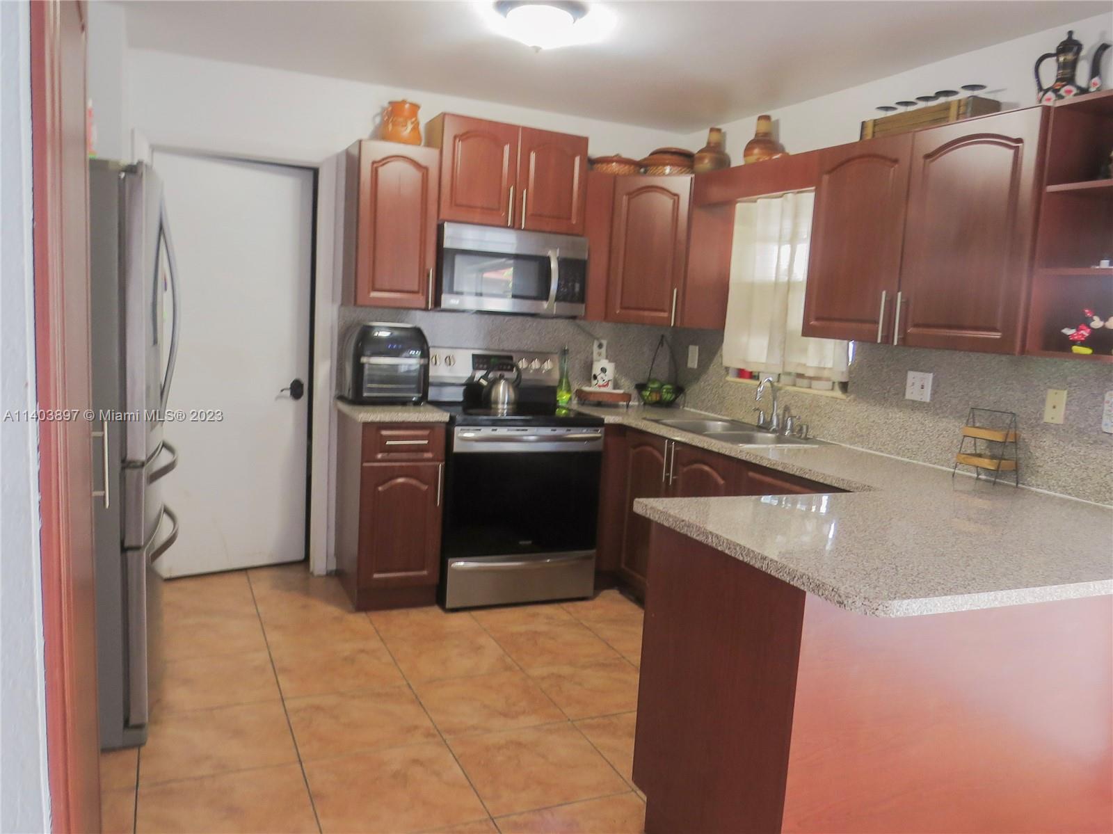 14225 Southwest 296th Street Homestead, FL 33033 - Photo 24 of 37 a kitchen with stainless steel appliances granite countertop a sink stove and refrigerator