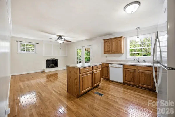a large kitchen with kitchen island granite countertop a stove a sink dishwasher and white cabinets with wooden floor