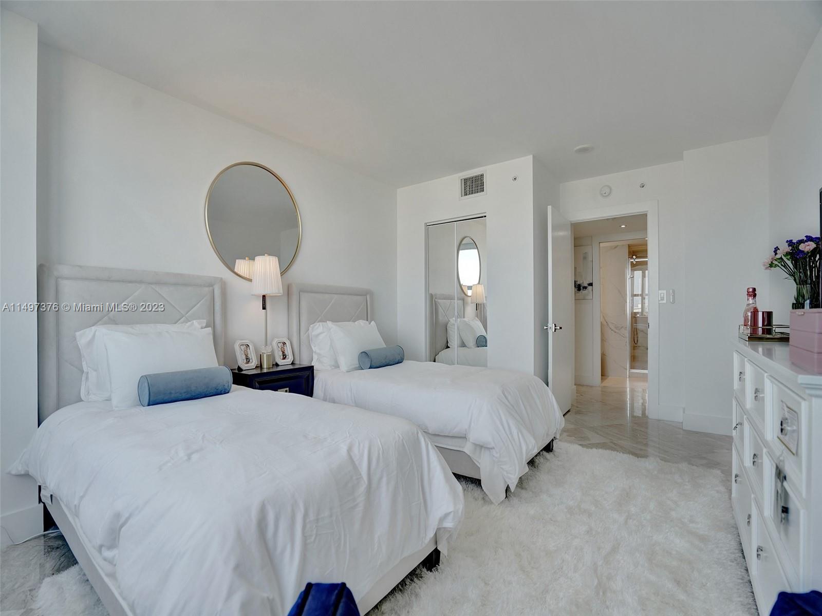 90 Alton Road, Unit 1109 Miami Beach, FL 33139 - Photo 13 of 23 a bedroom with two beds and a chandelier