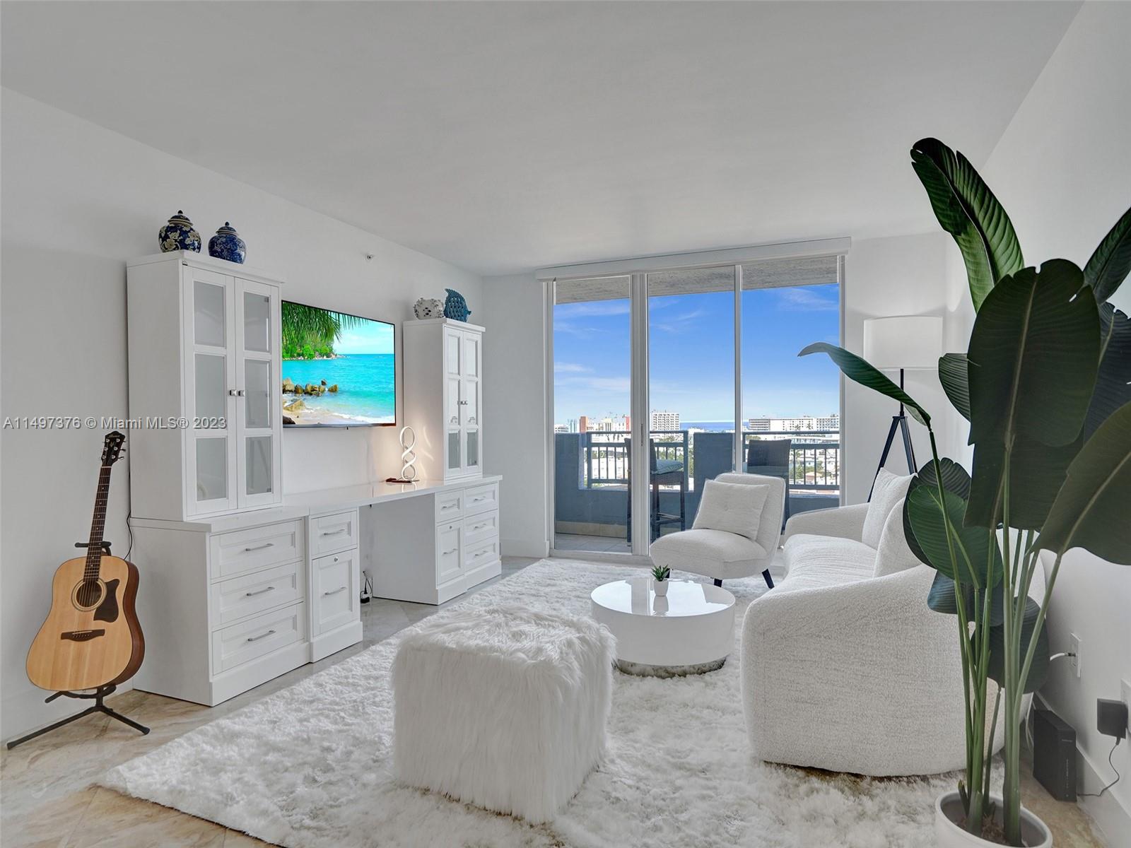 90 Alton Road, Unit 1109 Miami Beach, FL 33139 - Photo 14 of 23 a living room with furniture a flat screen tv and a floor to ceiling window