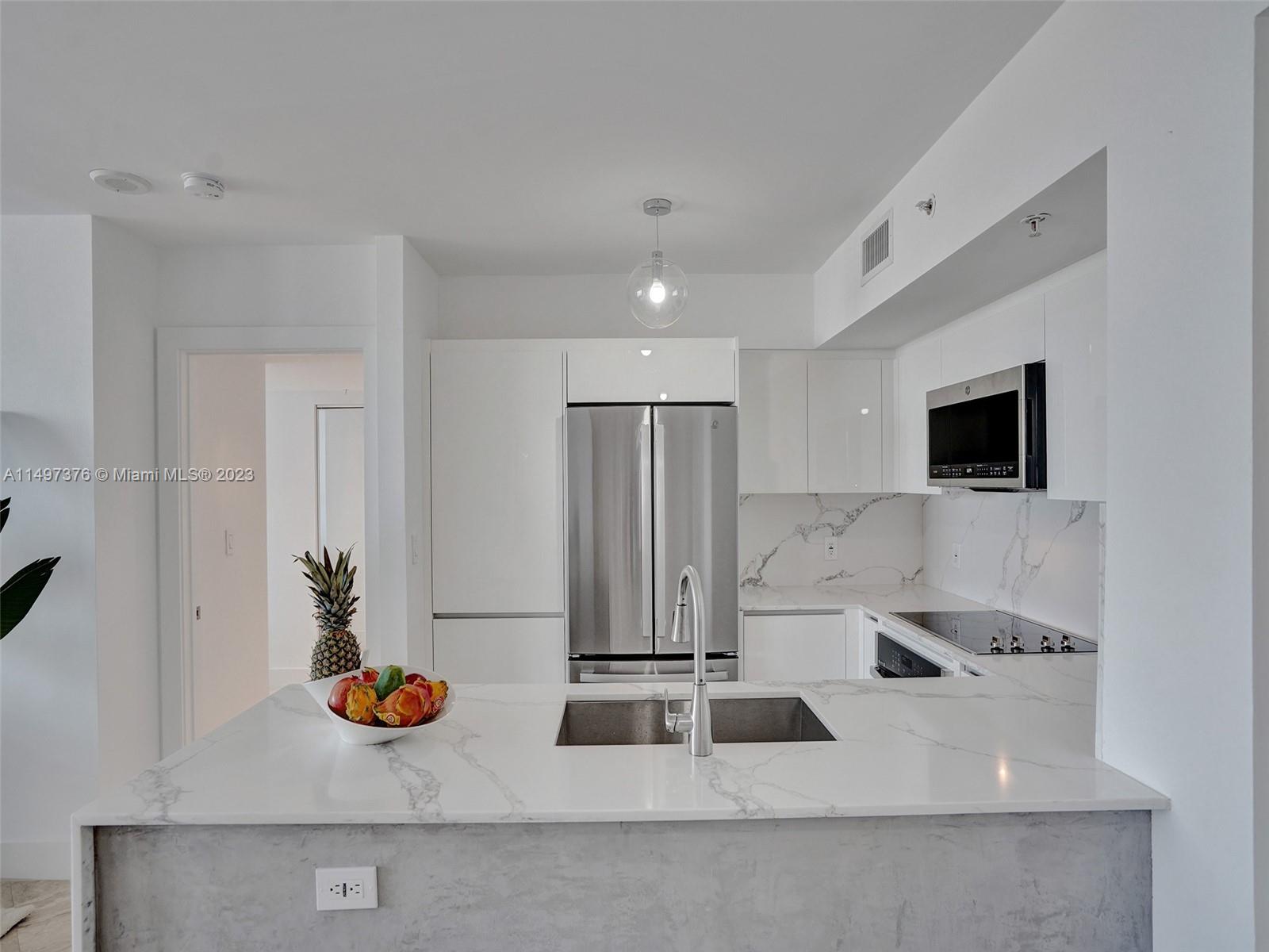 90 Alton Road, Unit 1109 Miami Beach, FL 33139 - Photo 6 of 23 a kitchen with a sink and a stove with white countertops