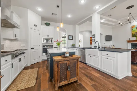 a kitchen with stainless steel appliances granite countertop a lot of counter space and wooden floors