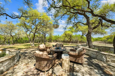 a view of a patio with couches chairs and a fire pit with large tree