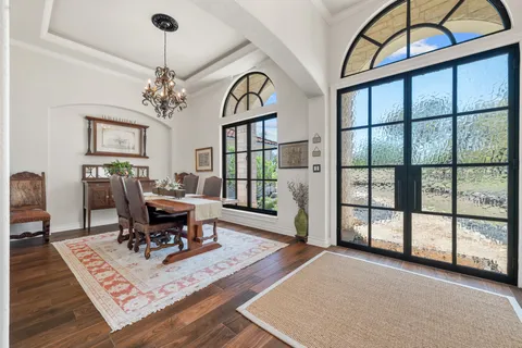 a living room with furniture a chandelier and wooden floor