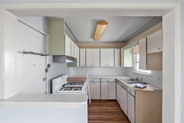 a kitchen with a sink a stove cabinets and a window