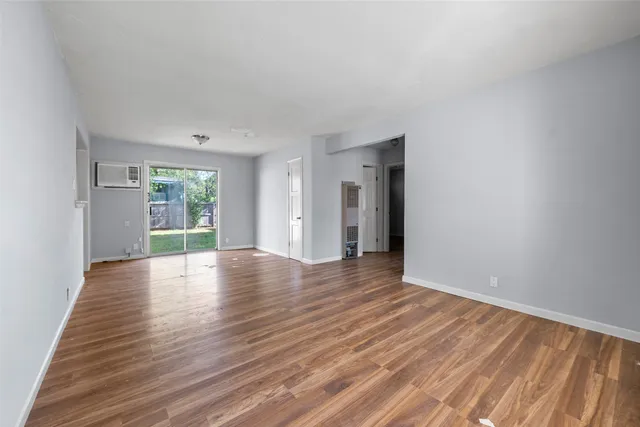 a view of an empty room with window and wooden floor
