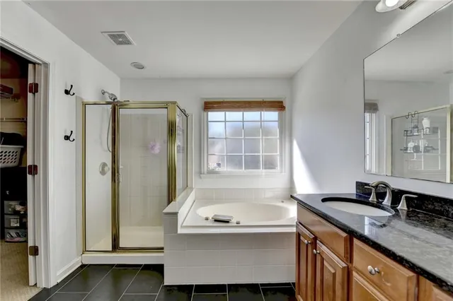 a bathroom with a granite countertop sink and mirror with bathtub