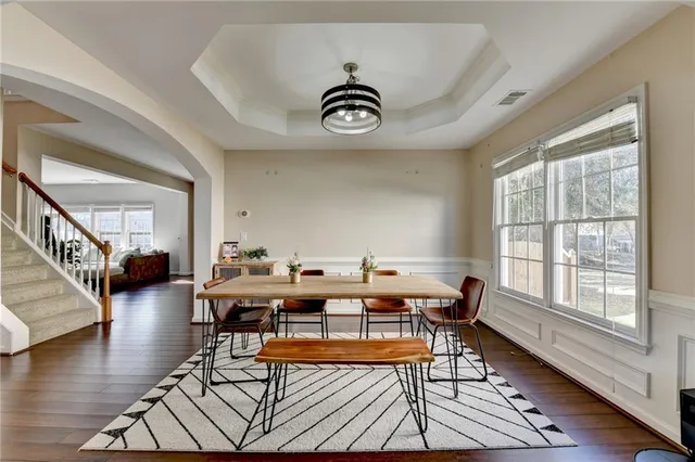 a dining room with wooden floor a chandelier a wooden table and chairs