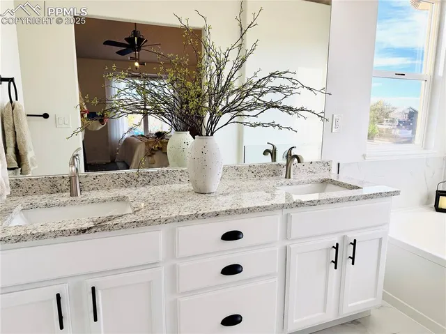 a bathroom with a granite countertop sink and a bathtub