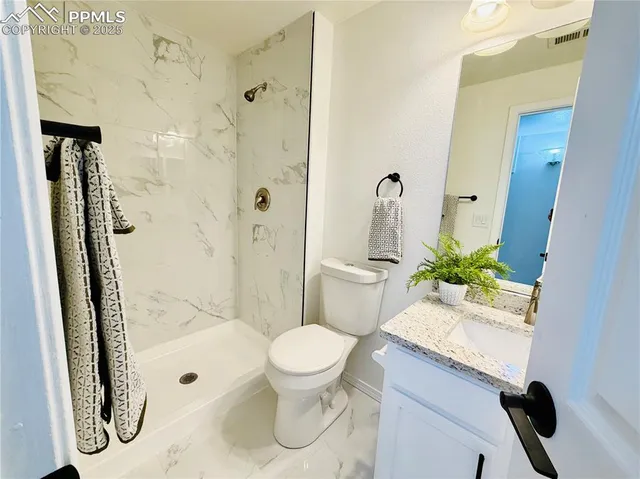 a white toilet sitting next to a bathroom sink and a mirror