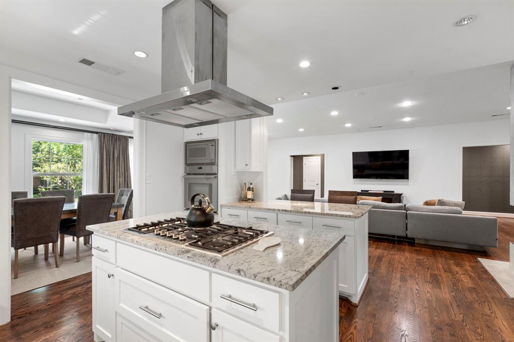 6446 Runnemede Lane Dallas, TX 75214 - Photo 6 of 23 a kitchen with stainless steel appliances a stove a sink dishwasher a refrigerator and a dining table with wooden floor