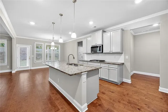 a kitchen with stainless steel appliances granite countertop a sink a stove and a wooden floors