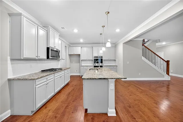 a kitchen with stainless steel appliances granite countertop a sink a stove and a refrigerator