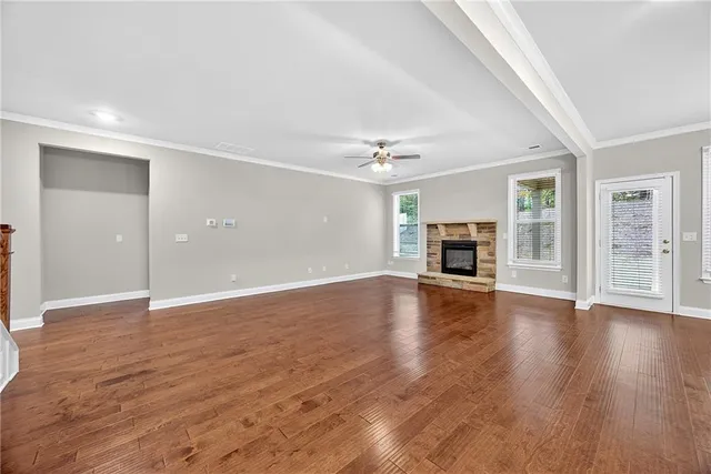 an empty room with wooden floor fireplace and windows