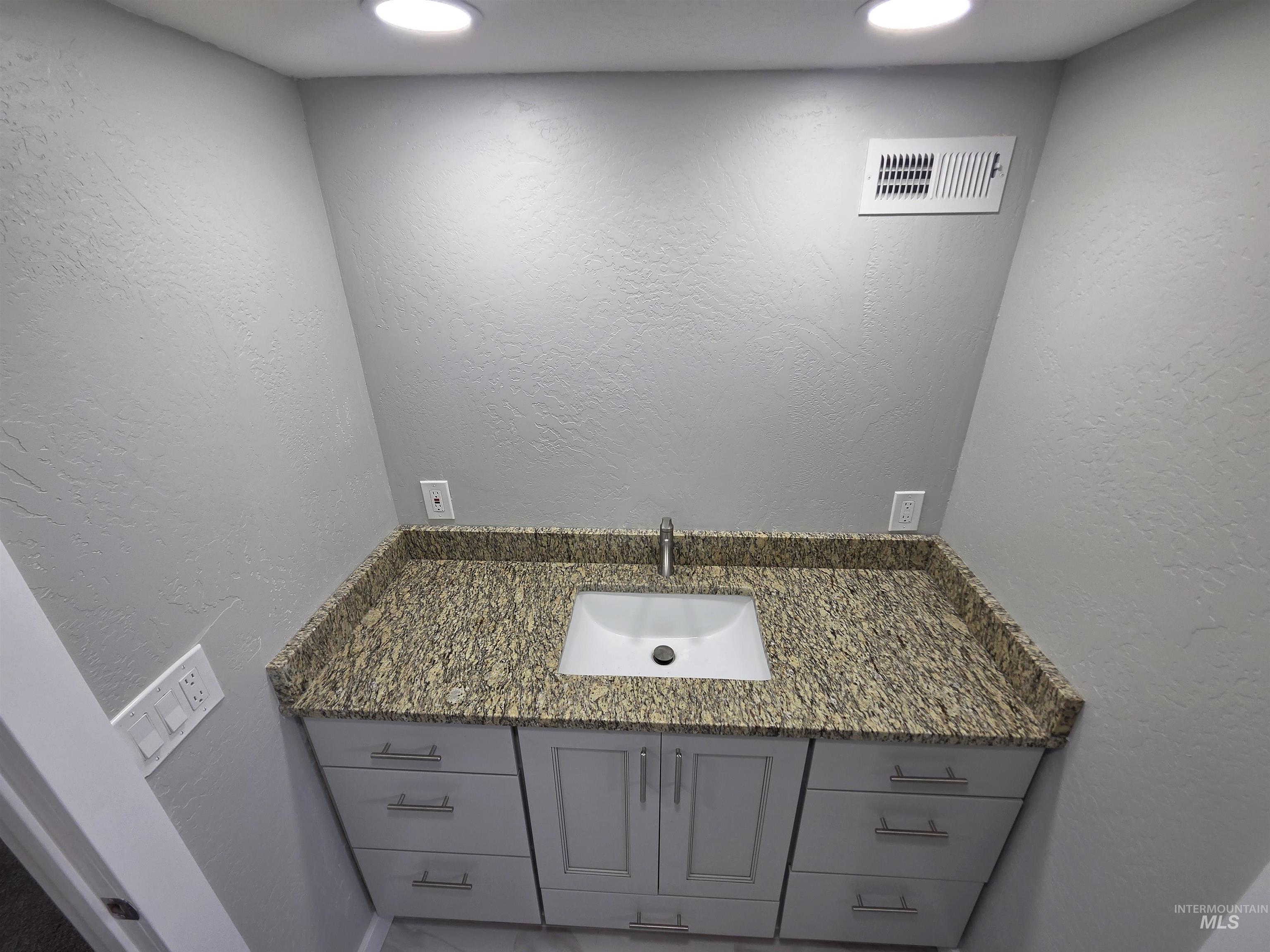 905 15th Drive Rupert, ID 83350 - Photo 12 of 20 Vanity featuring a rectangular undermount sink, a chrome faucet, and a speckled countertop