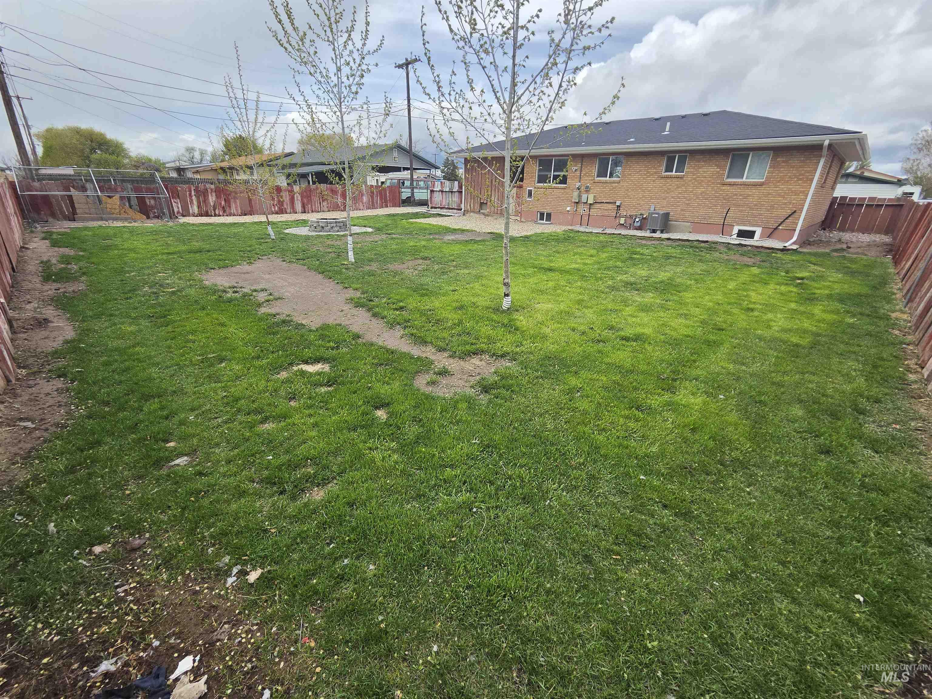 905 15th Drive Rupert, ID 83350 - Photo 18 of 20 Expansive backyard featuring a lush lawn, young trees, and a central fire pit area