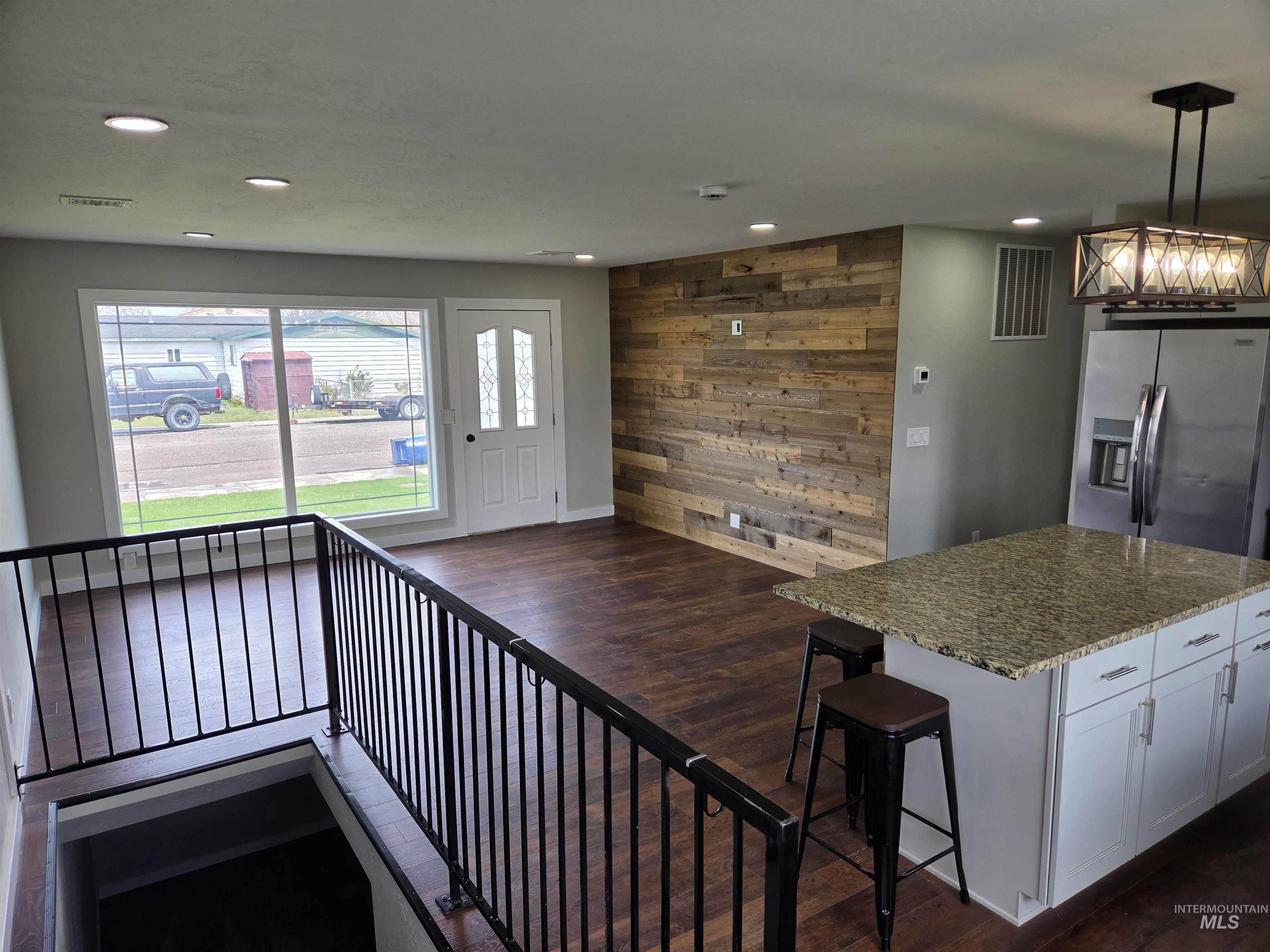 905 15th Drive Rupert, ID 83350 - Photo 4 of 20 Open-concept living space featuring wood-finish flooring, recessed lighting, and a prominent wood-panel accent wall