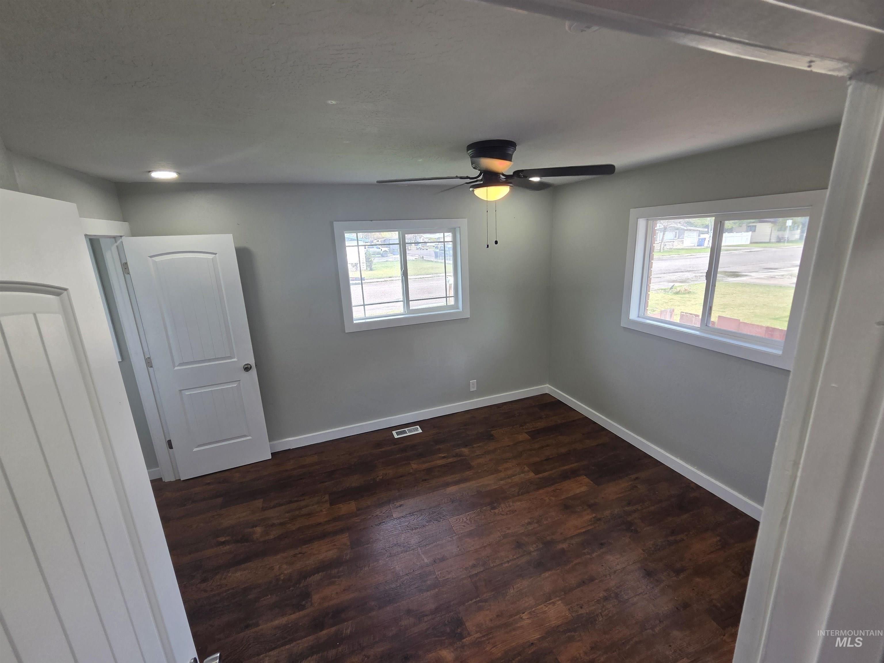 905 15th Drive Rupert, ID 83350 - Photo 7 of 20 Room featuring wood-finish flooring, two large windows, a ceiling fan with integrated lighting, recessed lighting, and a white interior door