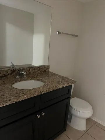 a bathroom with a granite countertop sink and a toilet
