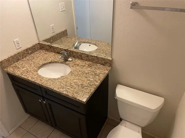 a bathroom with a granite countertop sink and a toilet
