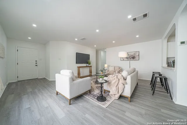 a living room with furniture a wooden floor and a flat screen tv