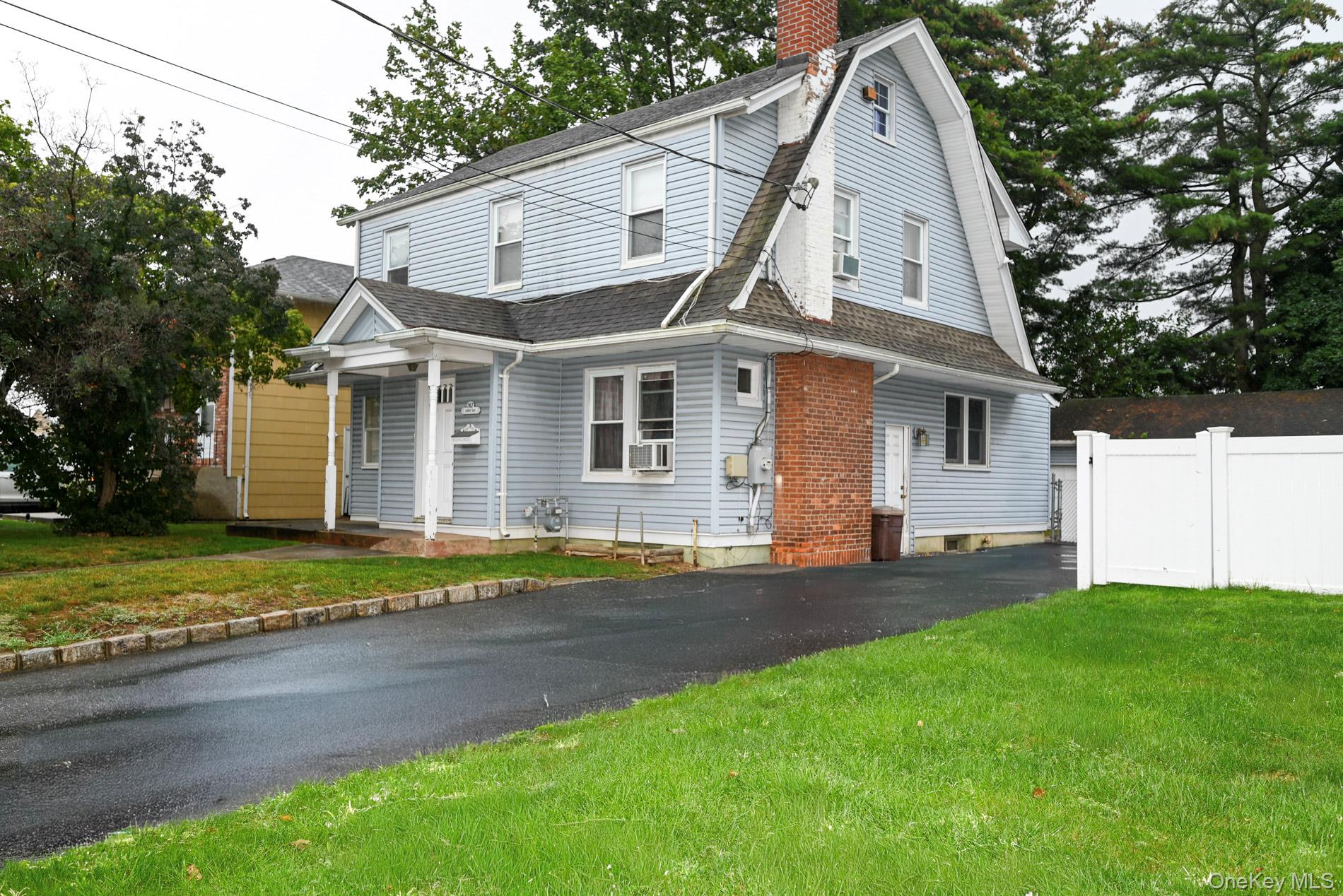 a view of a yard in front of a house with large trees