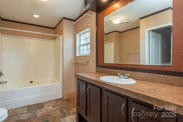 a bathroom with a granite countertop sink a toilet and shower