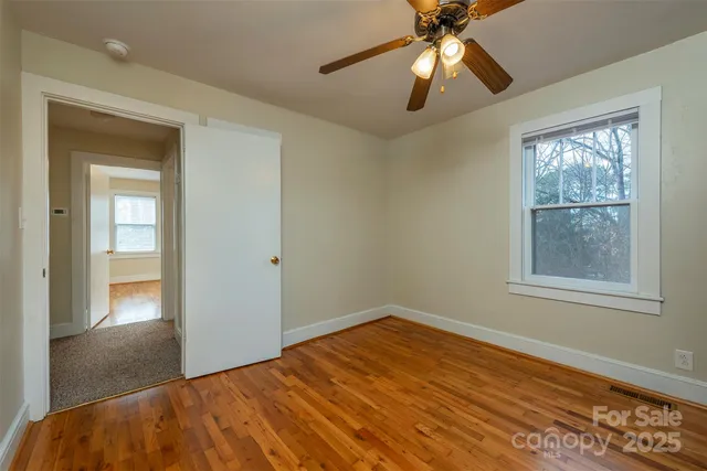 a view of empty room with wooden floor and fan