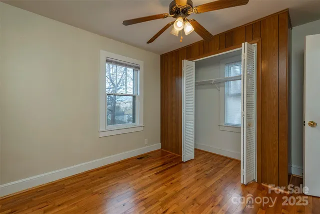 an empty room with wooden floor closet and windows