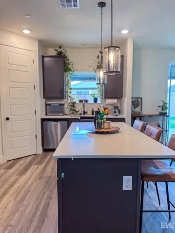 a kitchen with kitchen island granite countertop a sink cabinets and stainless steel appliances