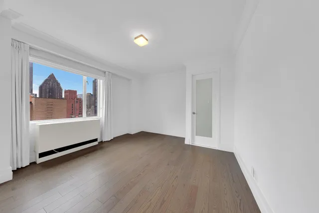 a view of an empty room with a window and wooden floor