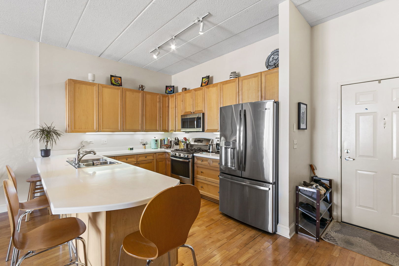 1301 West Washington Boulevard, Unit 508 Chicago, IL 60607 - Photo 3 of 17 a kitchen with a refrigerator a stove and a dining table with wooden floor