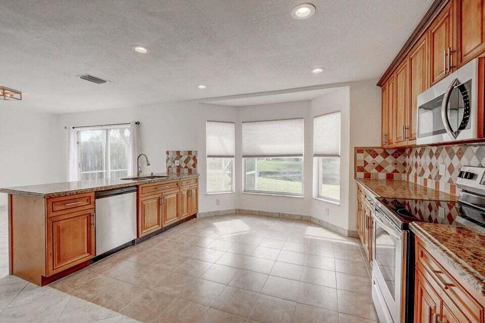 10758 Lake Jasmine Drive Boca Raton, FL 33498 - Photo 3 of 34 a large kitchen with stainless steel appliances granite countertop a stove and a sink
