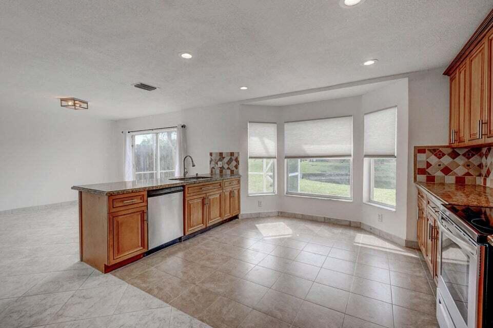 10758 Lake Jasmine Drive Boca Raton, FL 33498 - Photo 4 of 34 a large kitchen with stainless steel appliances granite countertop a stove a sink and a refrigerator