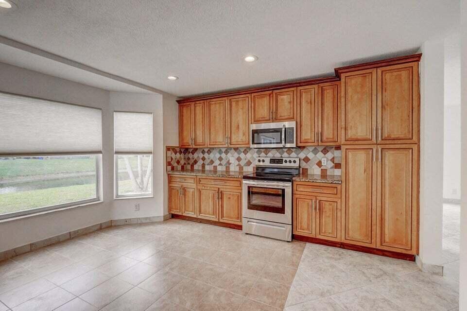 10758 Lake Jasmine Drive Boca Raton, FL 33498 - Photo 5 of 34 a kitchen with white cabinets and white appliances