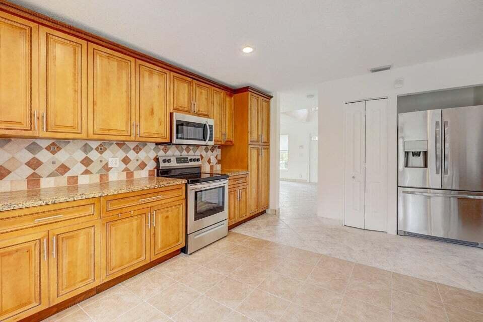 10758 Lake Jasmine Drive Boca Raton, FL 33498 - Photo 6 of 34 a kitchen with stainless steel appliances granite countertop a refrigerator stove top oven and sink with large window