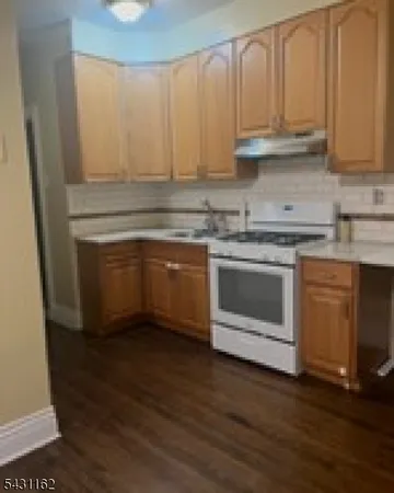 a kitchen with granite countertop a stove a sink and a microwave