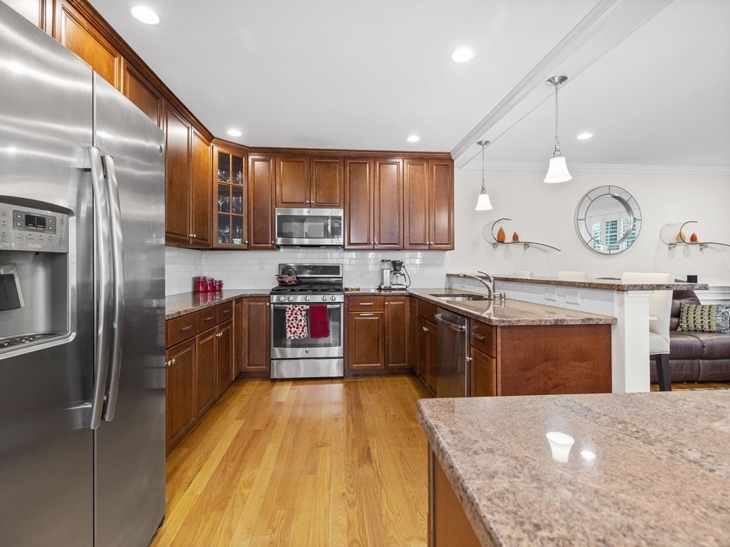 6 Robinson Road, Unit 3 Lexington, MA 02420 - Photo 5 of 38 a large kitchen with stainless steel appliances granite countertop a stove a refrigerator and a sink with wooden cabinets