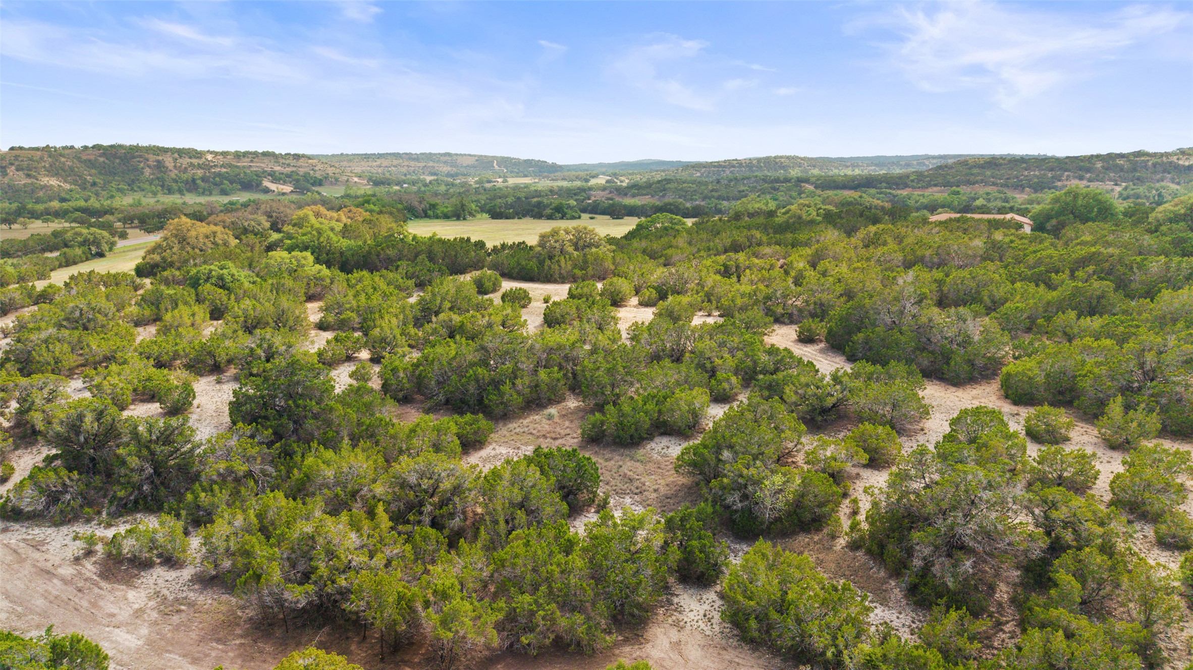 2966 Rm 165 Dripping Springs Dripping Springs, TX 78620 - Photo 2 of 23 Expansive acreage featuring dense natural tree coverage and varied terrain, with distant rolling hills under a clear sky
