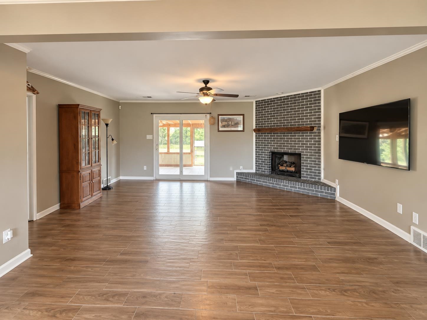 3771 West Union Road Millington, TN 38053 - Photo 6 of 16 Wood-finish flooring, corner fireplace with a brick surround, wood mantel, ceiling fan, and sliding glass doors